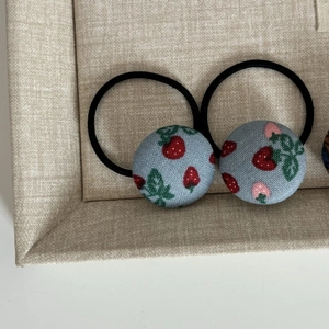 Vue macro d'élastiques à cheveux en tissu bleu avec motifs de baies et feuilles