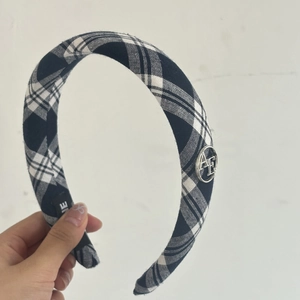 Close-up of blue plaid headband featuring a round silver AE metal buckle detail