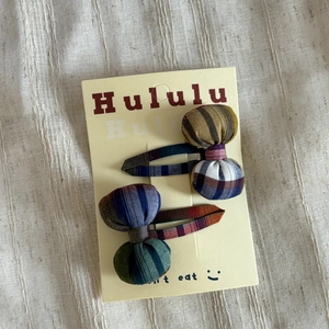 Close-up of colorful checkered padded bow hair clips on a branded paper card