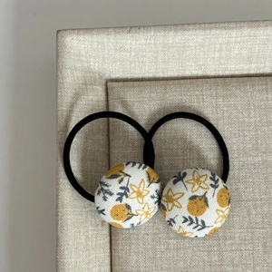 Détail de chouchous à bouton en tissu floral avec fleurs jaunes et élastique noir