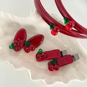Detail of red cherry hair accessories including headband and clips on shell tray