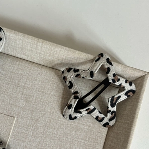 Star-shaped leopard print BB hair clip with plush fabric on a beige display stand
