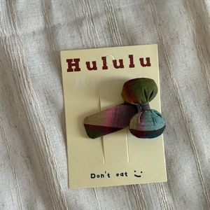 Detail of a colorful plaid fabric bow hair clip on a display card for girls