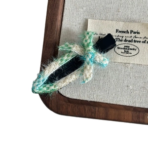 Blue and white tweed bow hair clip with duckbill clip on a wooden display background