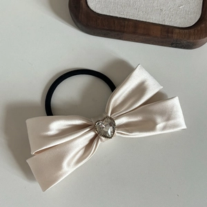 Dettaglio dell'elastico per capelli in raso beige con strass a forma di cuore