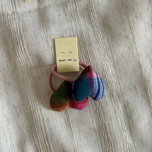 Detail of colorful plaid stuffed heart charms on an elastic pink fabric hair tie