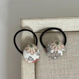 Gros plan d'élastiques à cheveux avec boutons en tissu fleuri vintage orange et blanc