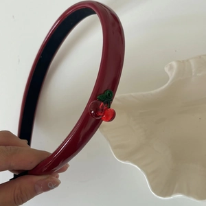 Detail view of glossy dark red headband with transparent cherry charm and anti-slip lining