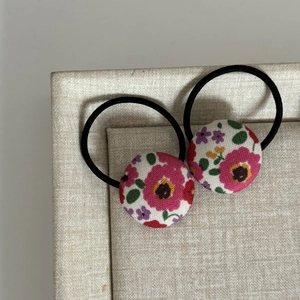 Vue détaillée de deux chouchous en tissu à fleurs sur une boîte beige de luxe
