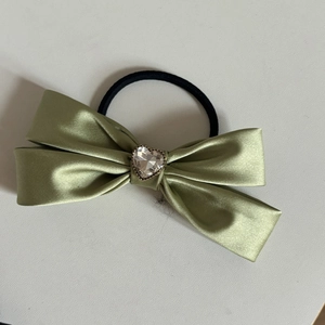 Dettaglio di un elastico in raso verde con uno strass scintillante a forma di cuore