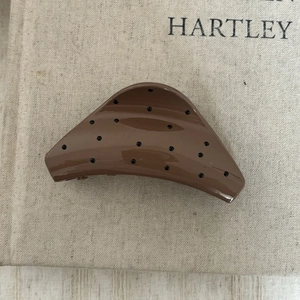Détail d'une pince à cheveux en résine marron ornée de strass noirs brillants