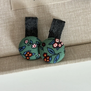 Détail des boutons en tissu vert foncé avec motif floral de style forêt naturelle