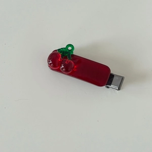 Translucent red cherry hair clip with green leaf detail and silver metal duckbill grip