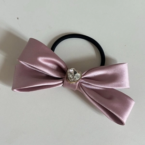 Dettaglio di un elastico in raso rosa con strass a forma di cuore scintillante al centro