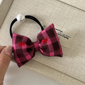 Pink plaid fabric bow hair scrunchie with embroidery and pearl accent on display box