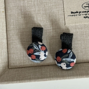 Détail de barrettes à fleurs en tissu avec motif de baies sur fond bleu marine