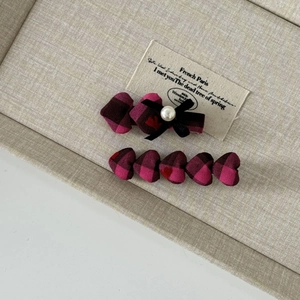Detail of rose pink plaid hair clips with bow, heart patterns and pearl on a tray