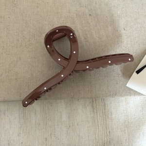 Gros plan d'une pince à cheveux marron à pois blancs avec un design noué élégant