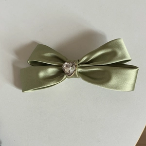 Dettaglio del fermaglio per capelli in raso verde con cristallo a cuore scintillante