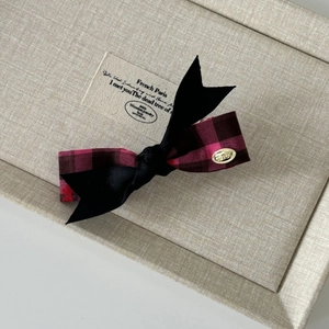 Detail of red buffalo plaid and black fabric bow clip with a gold LOVE metal buckle
