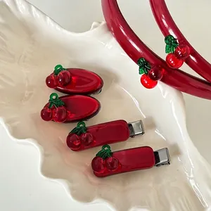 Red cherry hair accessory set including translucent acrylic clips and headband on ceramic plate