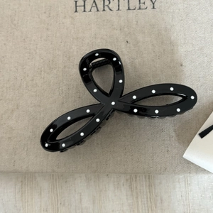 Détail d'une pince à cheveux noire à pois blancs avec un design de nœud élégant