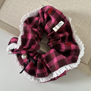 Detail of pink plaid scrunchie featuring white lace trim and a delicate pearl bow