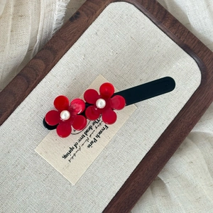 French vintage hair clip with red flowers and pearls on a sleek black metal duckbill base
