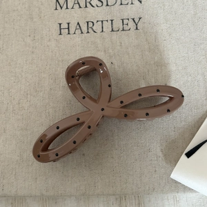 Détail de la pince à cheveux trèfle marron clair à pois sur fond de lin rustique