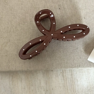 Gros plan détaillé d'une pince à cheveux marron à pois blancs avec un nœud élégant