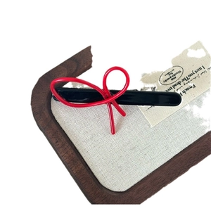French style red bow hair clip with black base on wooden tray and vintage paper background