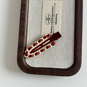 Detail of burgundy faux leather woven chain on a retro French style metal hair clip
