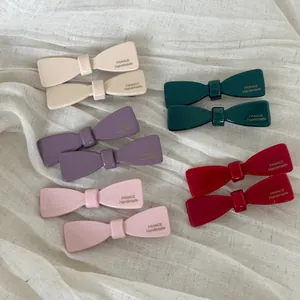 Close-up of gloss finish acetate bow hair clips in five colors with handmade details