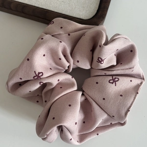 Detail of mauve oversized scrunchie with dark purple polka dots and bow pattern texture