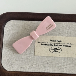 Pink acetate bow hair clip with handmade France lettering on a wooden tray