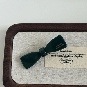 Detailed top view of a dark green bow hair clip with gold France handmade lettering