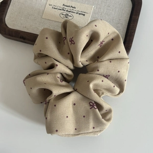 Close-up of beige bow polka dot hair scrunchie made of twill cotton on a wooden tray