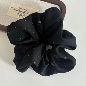 Vintage black scrunchie with pink polka dots and bow pattern on a rustic background