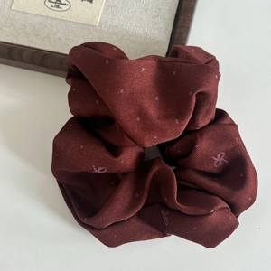 Detailed close-up of a burgundy scrunchie with polka dots and bow embroidery textures