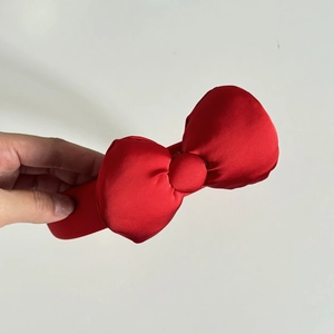 Detailed view of the red satin bow headband with smooth silk-like texture and wide frame