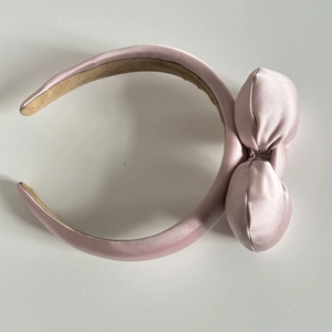 Close-up of pink satin bow headband with non-slip suede lining for skincare and makeup