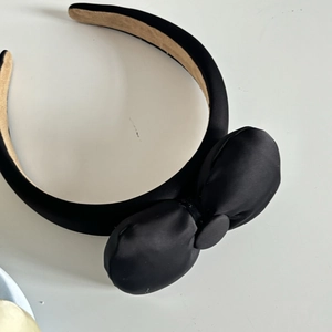 Detail of elegant black satin bow headband with non-slip beige inner lining for women