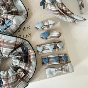 Retro blue plaid hair accessories set with heart clips and scrunchies on linen background