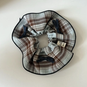 Blue plaid oversized hair scrunchie with denim bow detail and woven label on white background