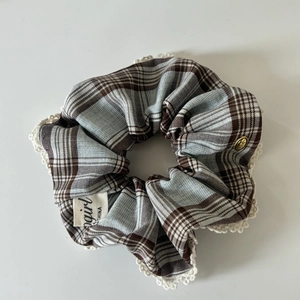 Detail of blue plaid hair scrunchie with crochet lace trim and vintage metal button accent