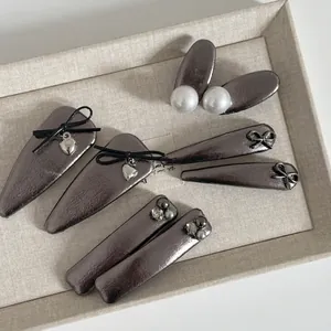 Metallic gunmetal bow hair clip set with pearls and heart charms on a beige display tray