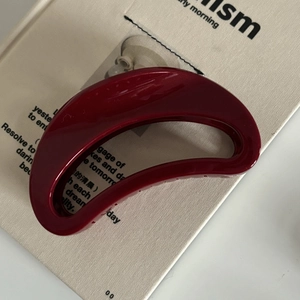 Détail d'une pince à cheveux bordeaux brillante posée sur un livre ouvert avec reflet