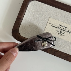 French vintage metallic leather bow hair clip with silver heart pendant on a display board