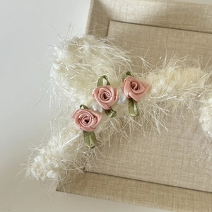 Détail d'un chouchou en peluche blanche avec roses en satin et perles élégantes