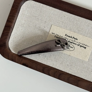 Detail of gunmetal grey hair clip with brushed metal texture and fine bow design